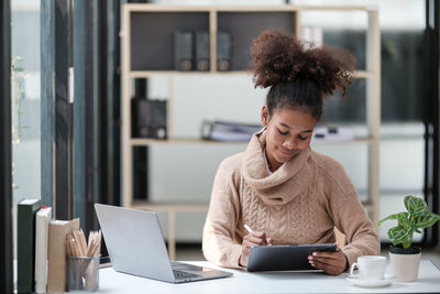 Portrait of young woman using laptop at home