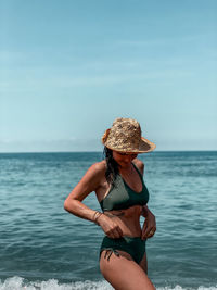 Rear view of woman standing at beach against sky