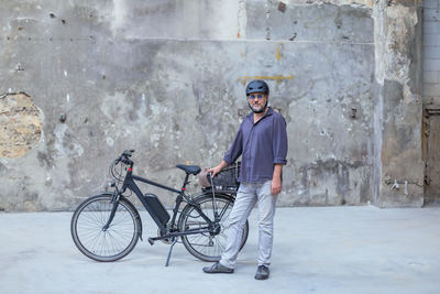 Portrait of man with bicycle standing in city