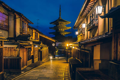 Illuminated street amidst buildings in city at night