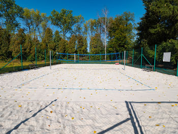 Closed beach volleyball court in fall season. autumn weather and fallen leaves on white sand.