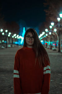 Portrait of smiling young woman standing at night