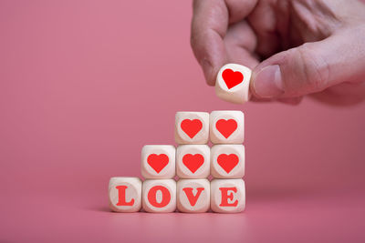 Close-up of hand holding toy over colored background