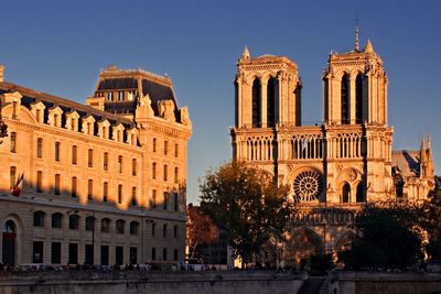 Historic buildings in city against clear blue sky