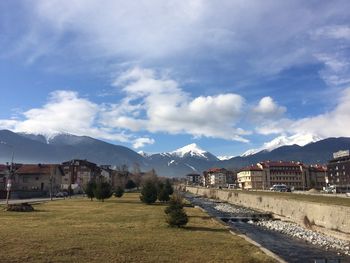 Scenic view of houses by mountains covered in snow against the sky