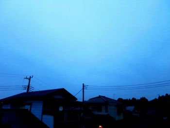 Low angle view of silhouette buildings against blue sky