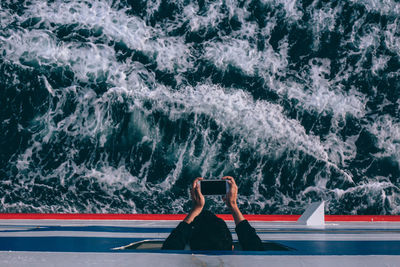 Directly above shot of man photographing in ship on sea