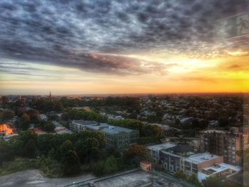 Cityscape against cloudy sky at sunset