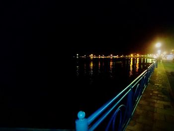 Illuminated city by river against clear sky at night