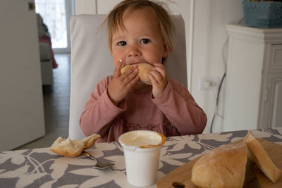 Small girl sitting at the table and having breakfast