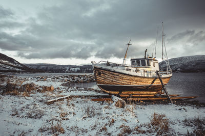 Norwegian wooden boat beached at sunset with snow