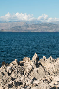 Rocks by sea against blue sky