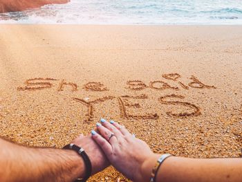 Midsection of text on sand at beach - marriage proposal 