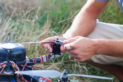 Cropped hands of mid adult man holding drone on field