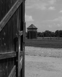 Wooden house on field by building against sky