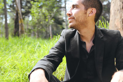 Smiling mid adult man looking away while sitting on grass