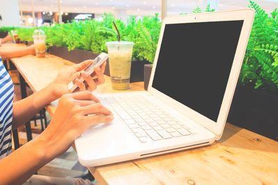 Midsection of woman using laptop on table