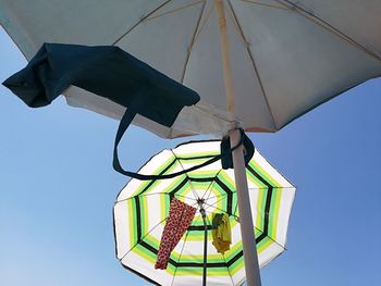 Low angle view of umbrellas against clear blue sky