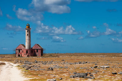 Lighthouse on field against sky