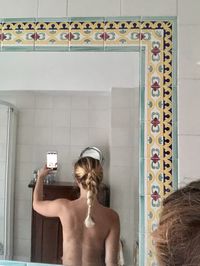 Rear view of shirtless woman standing in bathroom