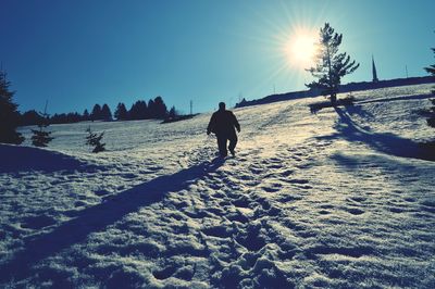 Rear view of silhouette man walking on snow covered landscape