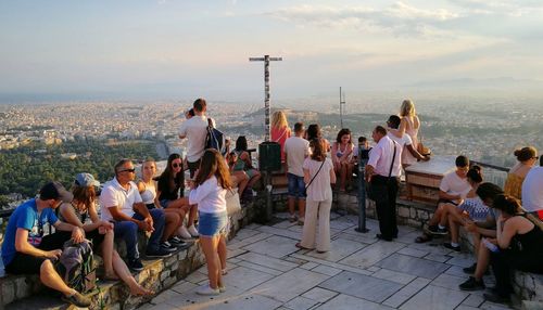 Group of people looking at sea by city against sky