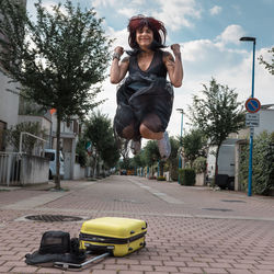 Woman in flowered dress walking towards the car with suitcase.