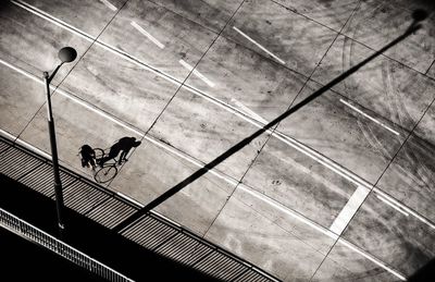 High angle view of man riding bicycle on street during sunny day