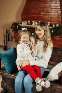 Portrait of smiling friends sitting on sofa at home