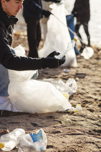 Young male environmentalist collecting plastic bottle by lake