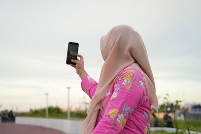 Midsection of woman using mobile phone against sky