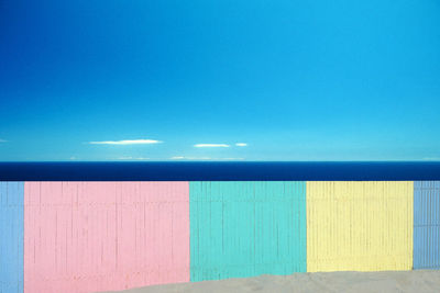 View of beach with fence against blue sky