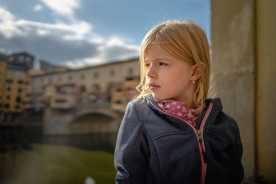 Portrait of a girl looking away, in front of medieval bridge, ponte vecchio, florenz italy