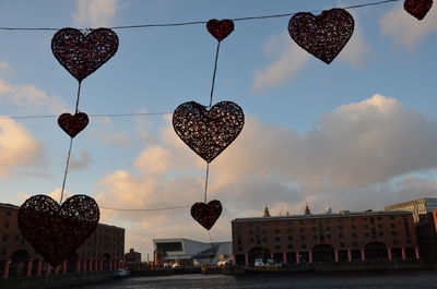 Low angle view of heart shape hanging against sky