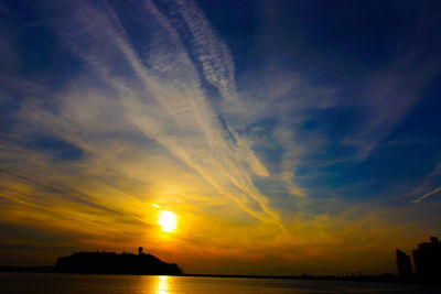 Scenic view of sea against dramatic sky during sunset