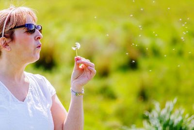 Mature woman blowing dandelion