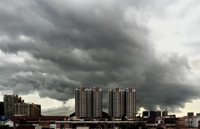 Low angle view of modern buildings against cloudy sky