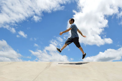 Low angle view of man jumping against sky