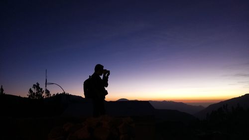 Silhouette man photographing at sunset