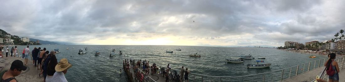 Panoramic view of people on boats in sea against sky