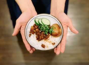 High angle view of hand holding bowl on table