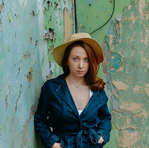 Portrait of young woman standing against wall