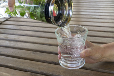 Midsection of person holding glass bottle on table