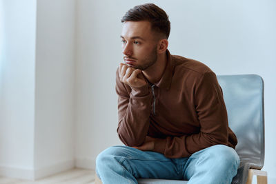 Young man using mobile phone while sitting on sofa at home