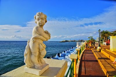 Statue by sea against blue sky