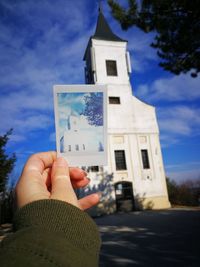 Person photographing building against sky