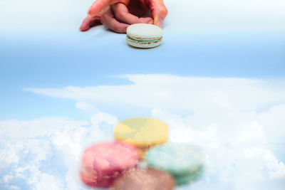 Digital composite image of person striking macaroon and cloudy sky