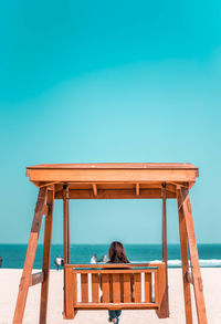 Rear view of woman by sea against clear sky