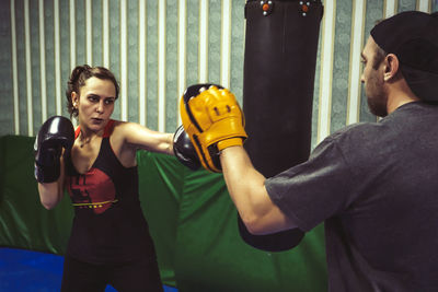 Female boxer training with male fitness instructor in gym