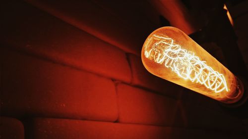 Close-up of illuminated light bulb against brick wall